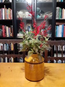 bright red sprays of pineapple sage blossoms in an earthenware vase